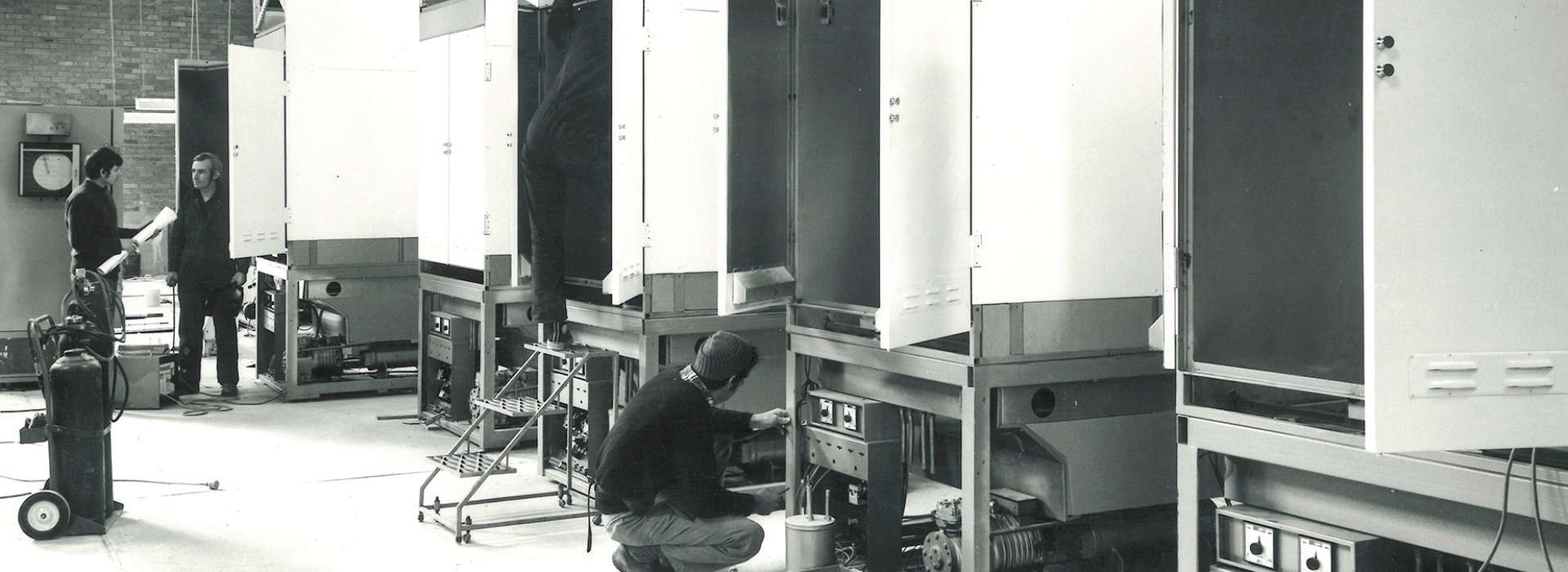 technicians working on industrial plant growth cabinets in a manufacturing facility.